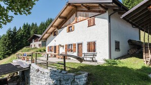 A two-story building with a stone foundation, wooden shutters, and a sloped roof. - Apartment "Baita Località Cap" with Garden & Mountain View (Roncone)