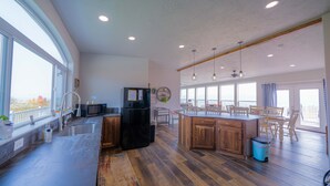 A spacious kitchen with a large island, wooden cabinets, and a view through the windows.