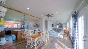 A spacious kitchen with wooden cabinets, a dining area with a wooden table and chairs, and a large window with a view of trees.