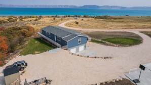A large house with a garage and a driveway leading to a sandy area.