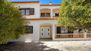 A two-story building with a stone-paved courtyard, white walls, and orange accents.