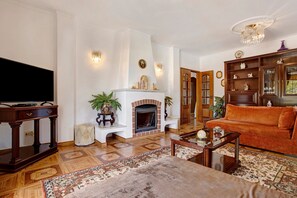 Una sala de estar con chimenea, televisión, sofá y mesa de centro.