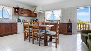 A spacious kitchen with wooden cabinets, a dining table with chairs, a microwave, and a view of the outside.