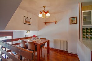 A dining area with a wooden table and chairs, a chandelier, and a radiator. - Club Villamar - Holiday home for 5 with communal pool (Sant Antoni de Calonge)