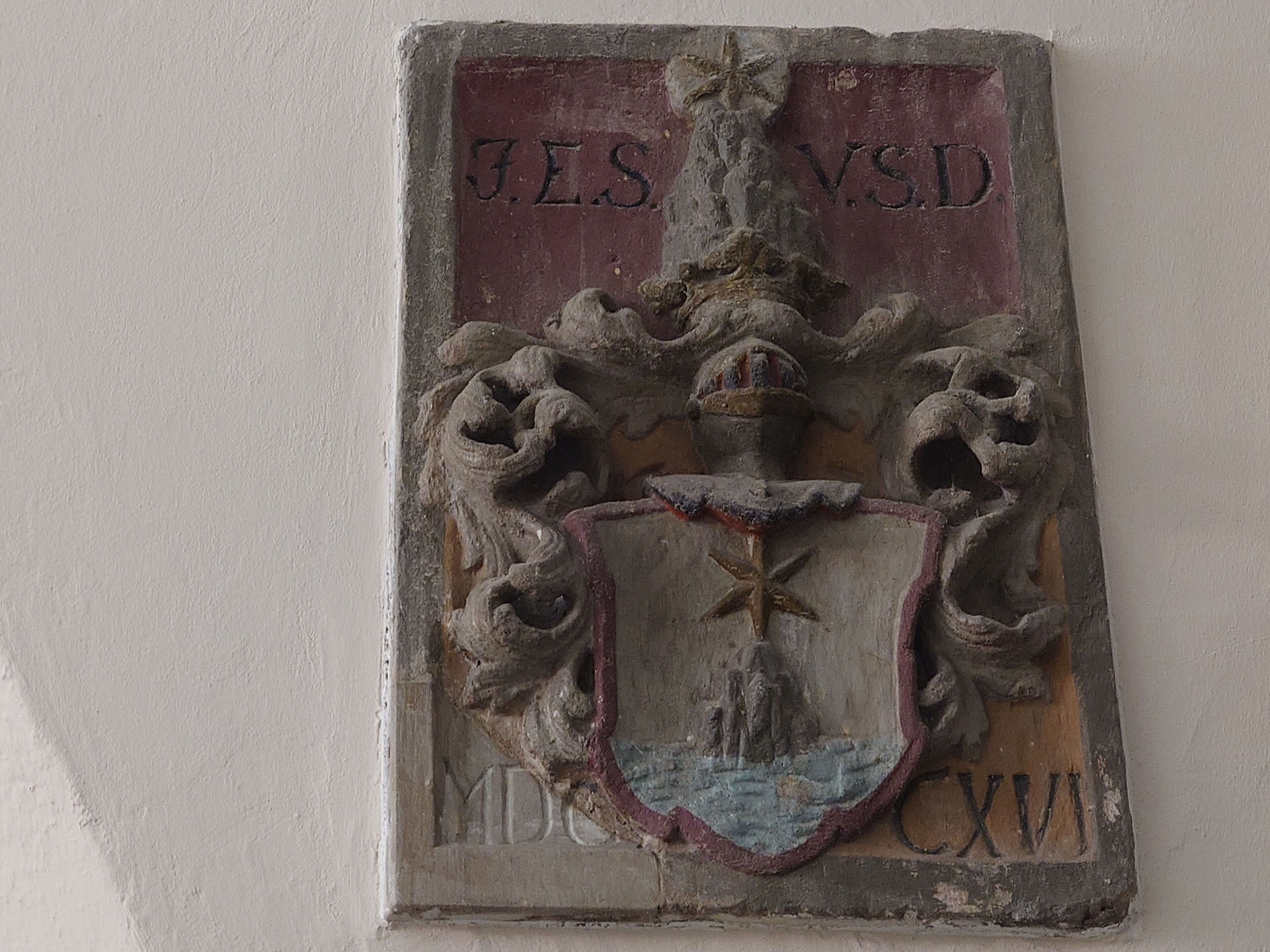 A stone plaque with carved coat of arms and inscriptions.