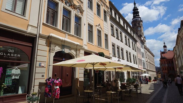 A cobblestone street with outdoor seating and a shop named "GLASER STIL GALERIE".