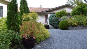 A house with a gravel driveway, surrounded by various potted plants and shrubs. - Entire room. Ocean,mountain view, hot tub,garden,deck,next to Mount Maxwell park (Salt Spring Island)