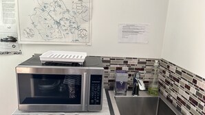 A kitchen with a stainless steel microwave, a sink, and a tiled backsplash. - Entire room. Ocean,mountain view, hot tub,garden,deck,next to Mount Maxwell park (Salt Spring Island)