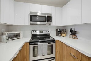 Una cocina moderna con armarios blancos, microondas integrado, horno de cocina y tostadora.