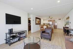 A modern living room with a flat-screen TV, a coffee table, and a seating area. - New Photos! Direct beach access+pool+parking (San Diego)