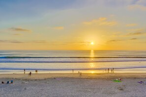 A beach with people walking and standing near the water, and a sunset in the background. - New Photos! Direct beach access+pool+parking (San Diego)