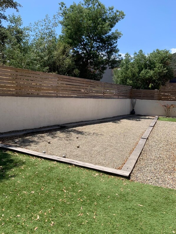 A garden with a gravel area, a wooden fence, and a grassy lawn.