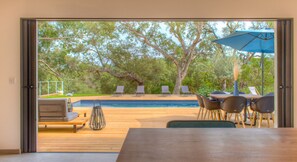 A wooden deck with a pool, outdoor seating, and a table with chairs.