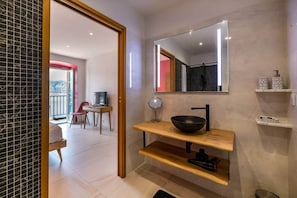 Une salle de bain moderne avec un grand miroir, un lavabo noir et une étagère en bois.