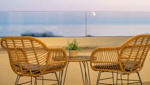 Ein Balkon mit Korbstühlen und einem kleinen Tisch, mit einem Blumentopf.