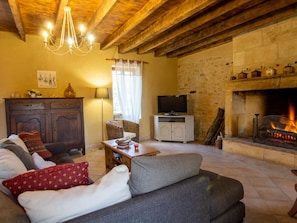A cozy living room with a fireplace, a television, and a stone wall.