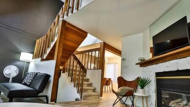 Una sala de estar moderna con escalera, chimenea y televisor de pantalla plana.