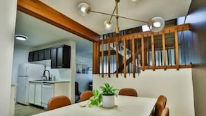 Un comedor con una mesa blanca, sillas marrones y una planta en maceta.
