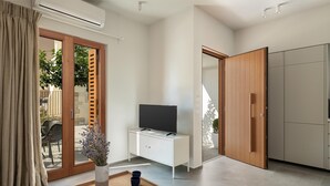 A modern living room with a TV, a wooden cabinet, and a sliding glass door leading to an outdoor area. - Lofos Casteli Sunlight (Chania)