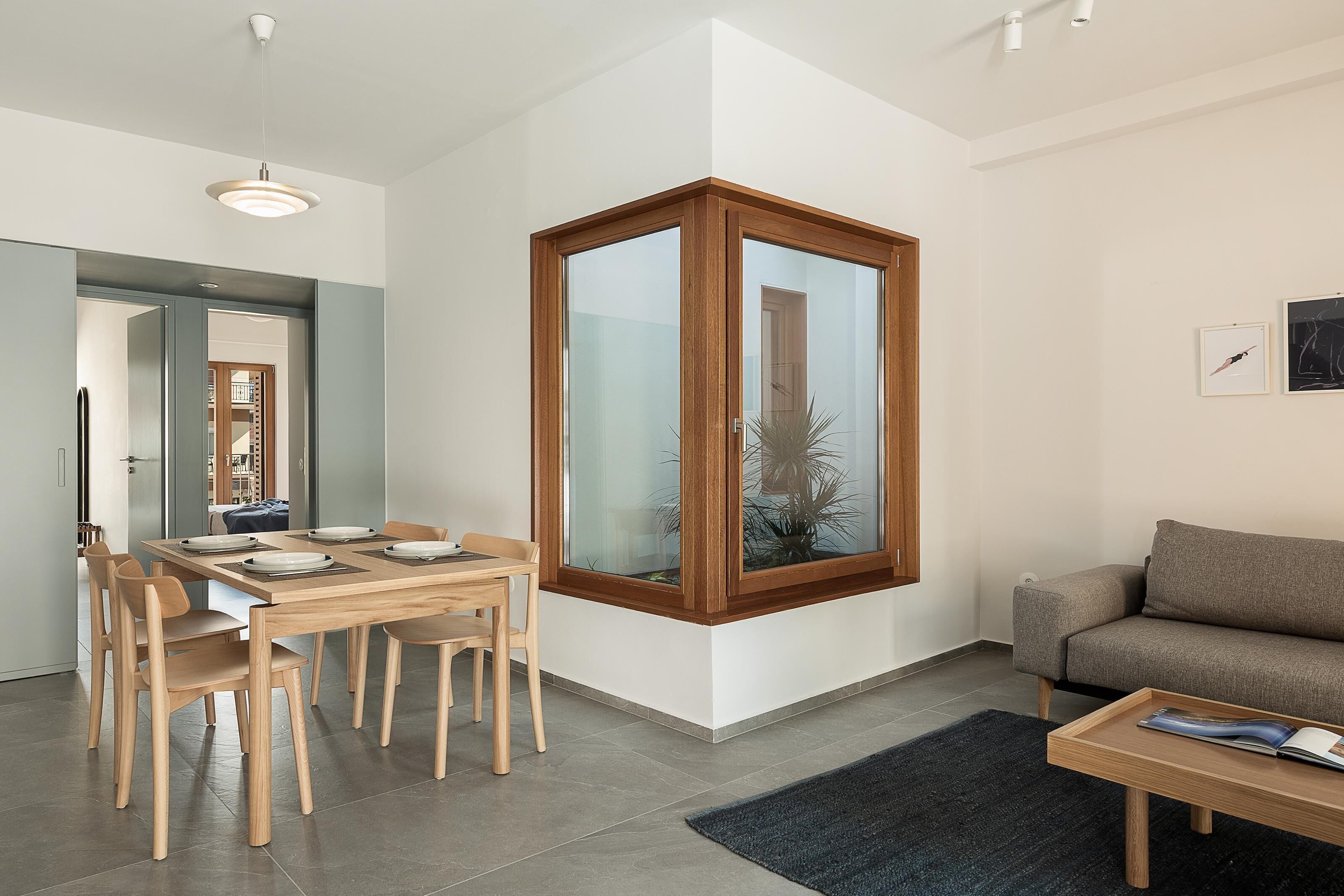 Uma sala de estar moderna com área de jantar, sofá e janela com vista para uma palmeira.