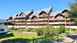 Een meerhoog hotel met balkons, een overdekt buitengebied en een omheinde tuin.