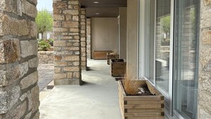 A covered outdoor area with stone walls, wooden planters, and large sliding glass doors. - Bel Appartement Proche de la Plage (56640 - ARZON)
