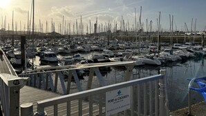 A marina with numerous boats docked, a sign indicating 'Port du Crouesty Morbihan', and a wooden walkway leading to the water. - Bel Appartement Proche de la Plage (56640 - ARZON)