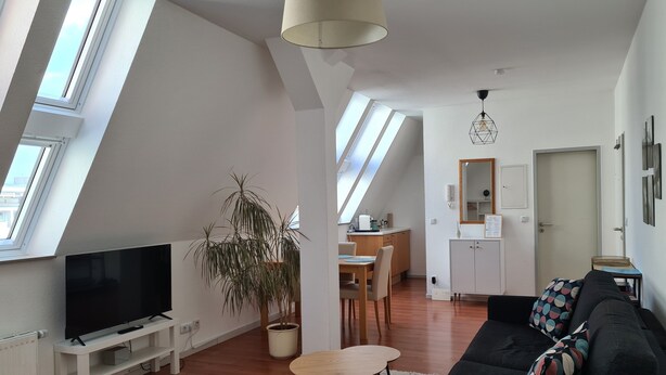 A modern loft apartment with a TV, sofa, dining area, and a large plant. - Lichtdurchflutetes Apartment im Herzen der City (Bielefeld)