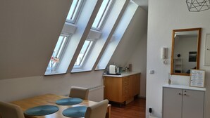A dining area with a wooden table, chairs, and a kitchen counter with a sink and cabinets. - Lichtdurchflutetes Apartment im Herzen der City (Bielefeld)
