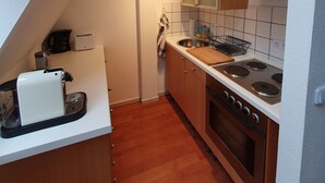 A modern kitchen with wooden cabinets, a stainless steel stove, and a white countertop. - Lichtdurchflutetes Apartment im Herzen der City (Bielefeld)