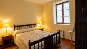 A bedroom with a wooden bed, two bedside lamps, a window with lace curtains, and a small table with a teddy bear. - Charming Quiet House Near Sarlat with Fireplace and Terrace (Tursac)