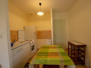 Una cocina compacta con una mesa de comedor, un refrigerador, una estufa y un lavamanos.