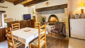 A rustic dining area with wooden furniture, a stone fireplace, and a television on a wooden cabinet.