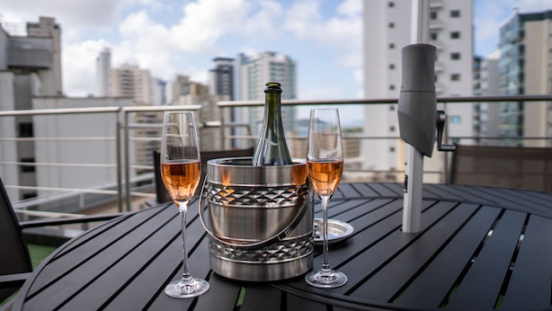 A table with a metallic bottle warmer containing a bottle and two glasses of wine.