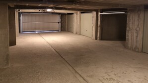 Eine Tiefgarage aus Beton mit drei geschlossenen Garagentoren und einem Betonboden.