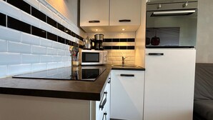 Une cuisine moderne avec des armoires blanches, un plan de travail noir, un four à micro-ondes encastré et une cuisinière.