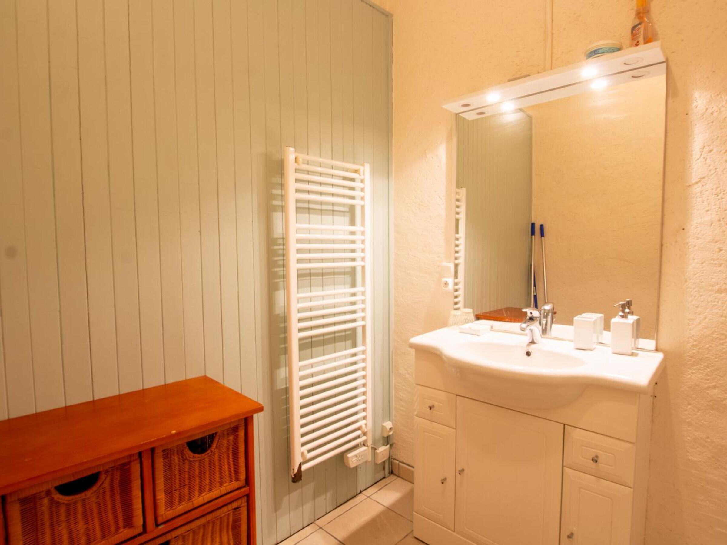 Une salle de bain avec un lavabo blanc, un miroir et un porte-serviettes.