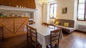 A cozy kitchen with wooden cabinets, a dining table, and a sofa. - Charming village house near Villefranche du Périgord, pets allowed, internet included (Loubejac)