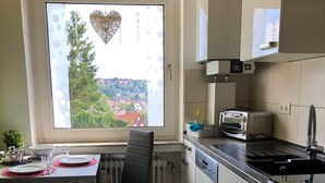 Et lille køkken med spiseplads, et vindue med udsigt og basale hårde hvidevarer.