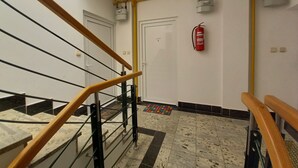 A staircase with wooden handrails, a fire extinguisher mounted on the wall, and a ceiling-mounted smoke detector. - Holiday apartment Lungomare, only 300m from the beach (Pula)