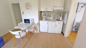 A compact kitchen with white cabinets, a microwave, a sink, and a small dining area with a table and chairs. - Holiday apartment Lungomare, only 300m from the beach (Pula)