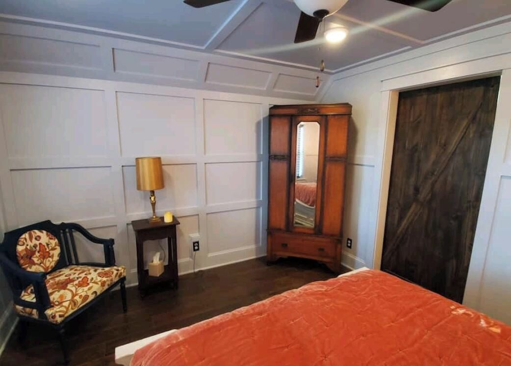 A bedroom with a bed, a dresser, a chair, and a mirror.
