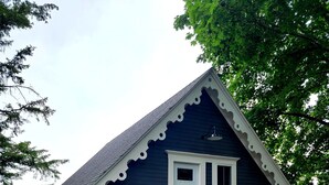 Ein Haus mit einer Holztreppe, die zu einer Veranda, einer Haustür und einer kleinen Blumenrabatte führt.