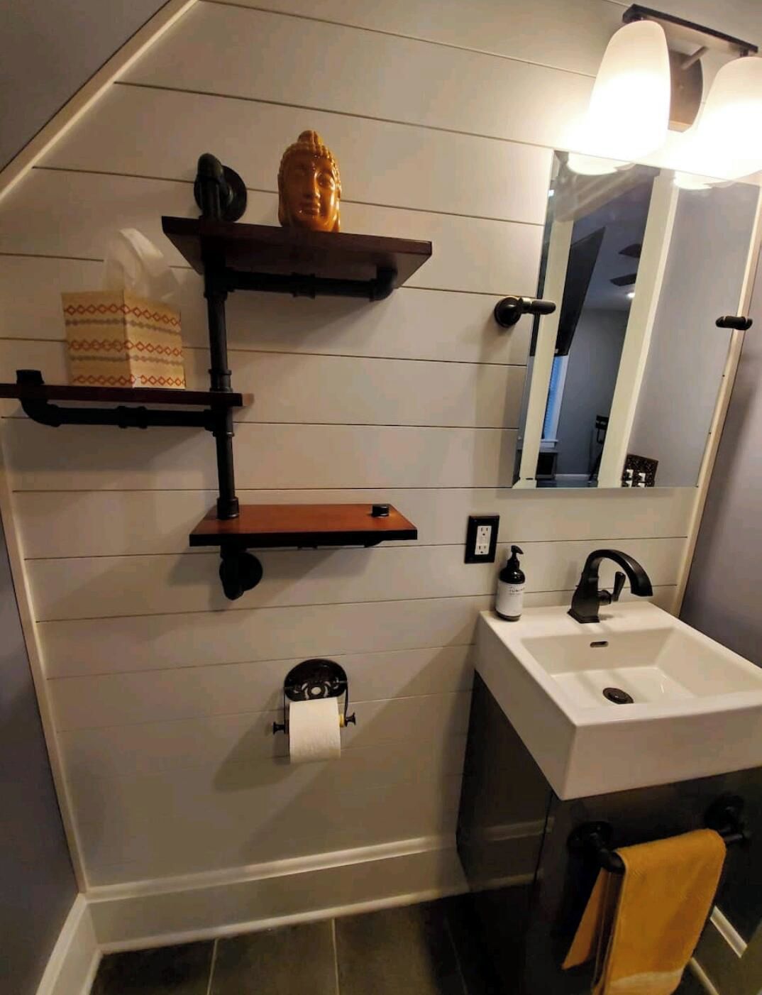 A bathroom with a white sink, a mirror, a toilet paper holder, and a towel rack.