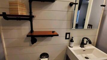 A bathroom with a white sink, a mirror, a toilet paper holder, and a towel rack.