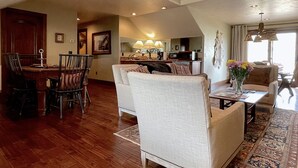 A spacious living area with a dining table, chairs, a sofa, and a kitchen in the background. - Studio 57- luxury apartment in the Wapiti Area! (Cody)
