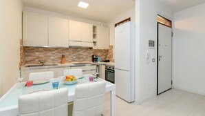 Eine moderne Küche mit weißen Schränken, einer gefliesten Spritzschutzwand und einem Essbereich mit Tisch für zwei Personen.