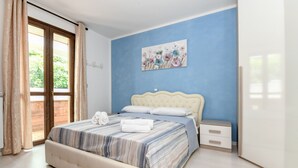 Ein Schlafzimmer mit einem großen Bett, einem Nachttisch, einem Bild an der Wand und Blick durch das Fenster.
