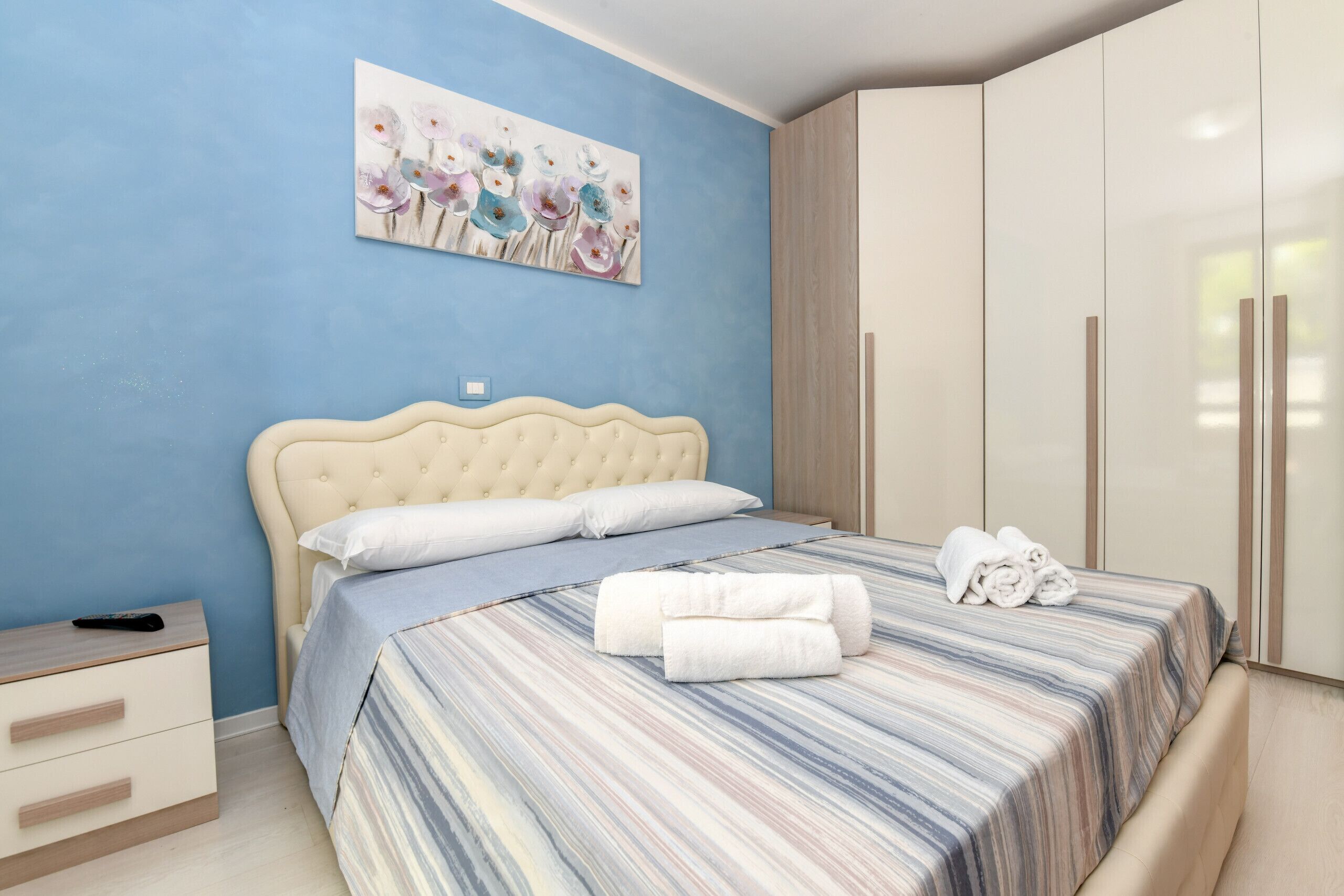 Une chambre à coucher avec un lit, une table de chevet, une armoire et un tableau au mur.