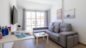 A modern living room with a grey sofa, a white coffee table, and a flat-screen TV. - Modern Apartment with pool in El Castillo - Home For Guest (Antigua - Fuerteventura)